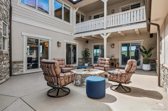 view of patio featuring a balcony and an outdoor living space with a fire pit