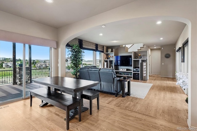 dining area with arched walkways, baseboards, recessed lighting, and light wood-style flooring