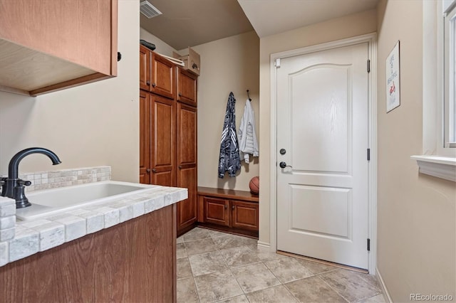 mudroom featuring visible vents, a sink, and light tile patterned floors
