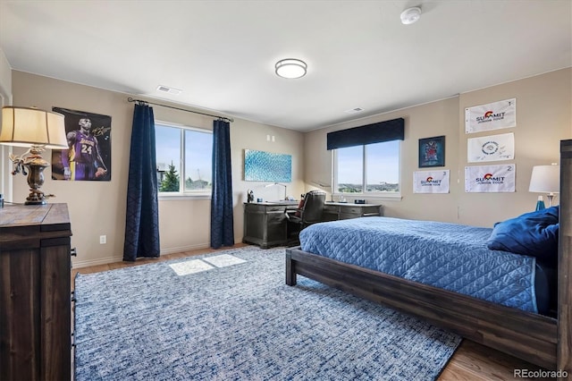 bedroom featuring visible vents, light wood-style floors, baseboards, and multiple windows