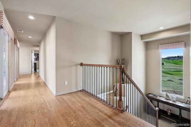 hall with a healthy amount of sunlight, an upstairs landing, recessed lighting, and wood finished floors