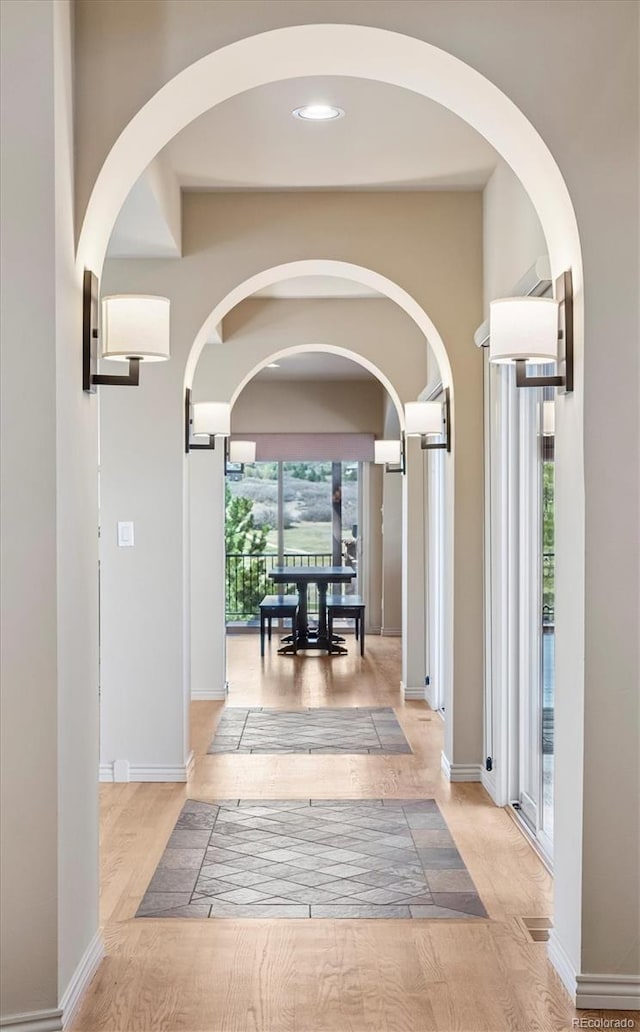 hall with arched walkways, baseboards, recessed lighting, and wood finished floors