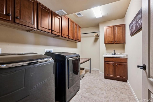 washroom featuring a sink, separate washer and dryer, cabinet space, and visible vents