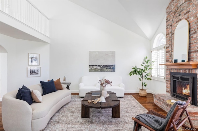 living room featuring wood-type flooring, a fireplace, and high vaulted ceiling