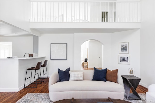 living room with dark hardwood / wood-style floors, a towering ceiling, and sink