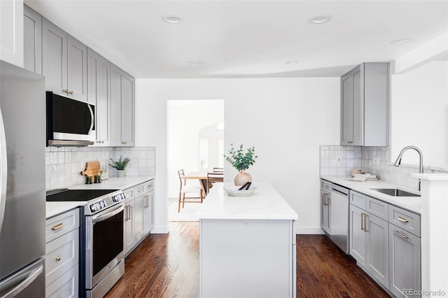 kitchen featuring appliances with stainless steel finishes, dark hardwood / wood-style flooring, backsplash, gray cabinetry, and sink