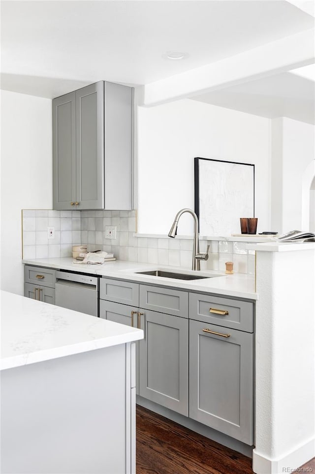 kitchen with gray cabinetry, sink, light stone counters, backsplash, and white dishwasher