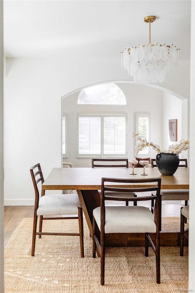 dining space with light hardwood / wood-style floors and a notable chandelier