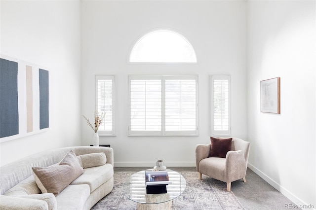 living room featuring carpet flooring, a towering ceiling, and plenty of natural light