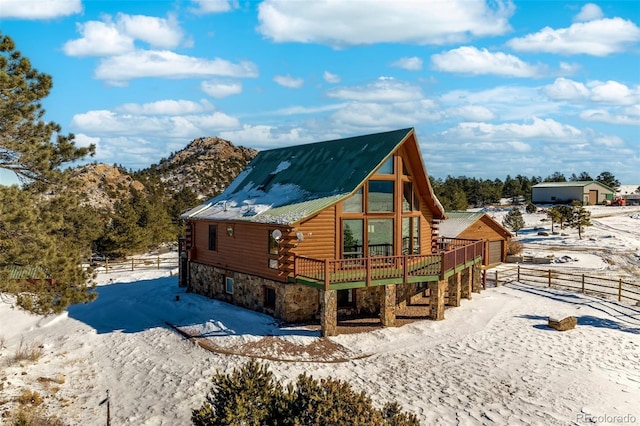 snow covered rear of property with a deck with mountain view