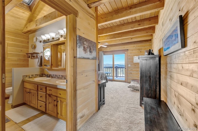 bathroom featuring wood ceiling, a skylight, wooden walls, vanity, and beamed ceiling