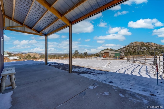 snow covered patio with a mountain view and an outdoor structure