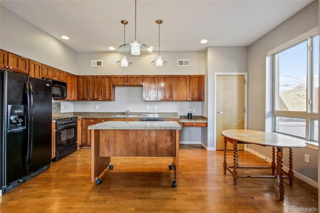 kitchen with black appliances, visible vents, pendant lighting, and a center island