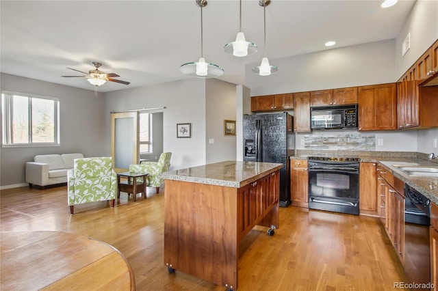 kitchen with stone countertops, pendant lighting, brown cabinets, and black appliances