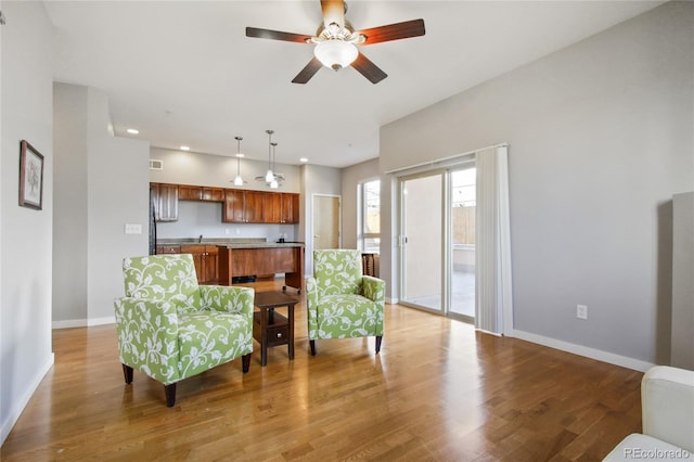 living area featuring recessed lighting, light wood-type flooring, a ceiling fan, and baseboards