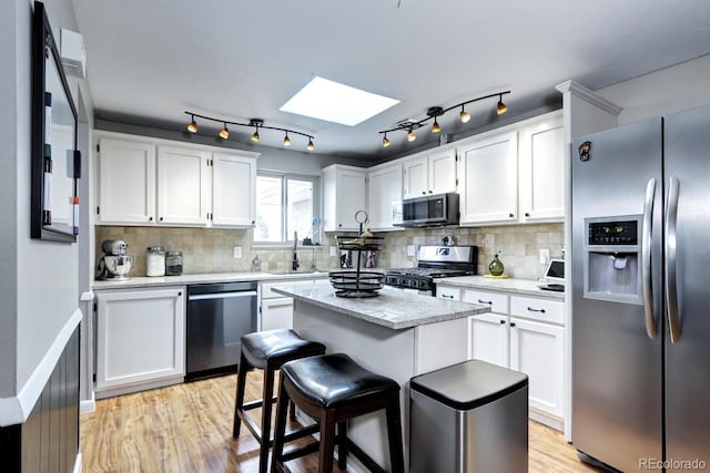 kitchen featuring white cabinetry, a sink, appliances with stainless steel finishes, and a skylight