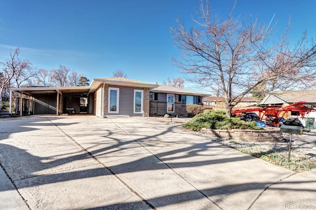 view of front of property featuring brick siding, driveway, and an attached carport
