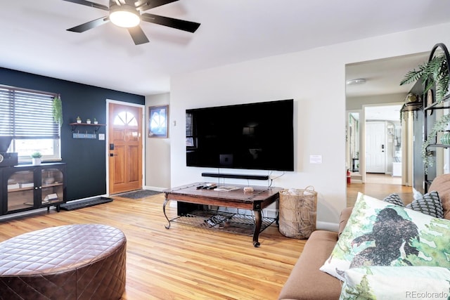 living room featuring a ceiling fan, baseboards, and light wood-style flooring