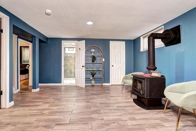 living area with a wood stove, baseboards, and wood finished floors