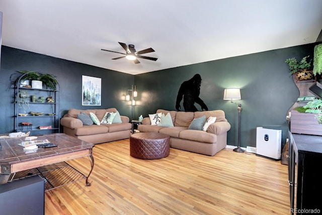 living area featuring ceiling fan, baseboards, and light wood-style floors
