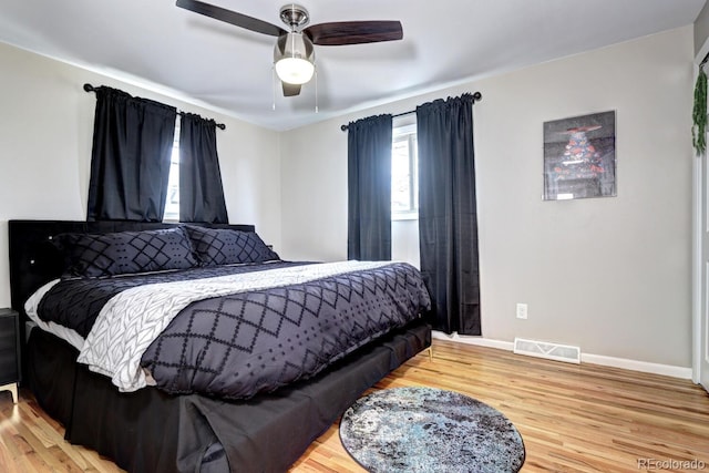 bedroom with baseboards, ceiling fan, visible vents, and wood finished floors