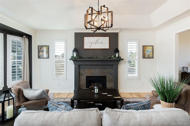 living room with a fireplace, baseboards, a raised ceiling, and wood finished floors