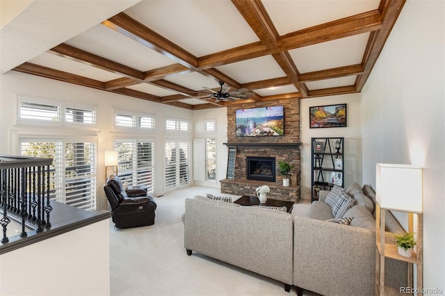 living room with coffered ceiling, beamed ceiling, a stone fireplace, and carpet flooring