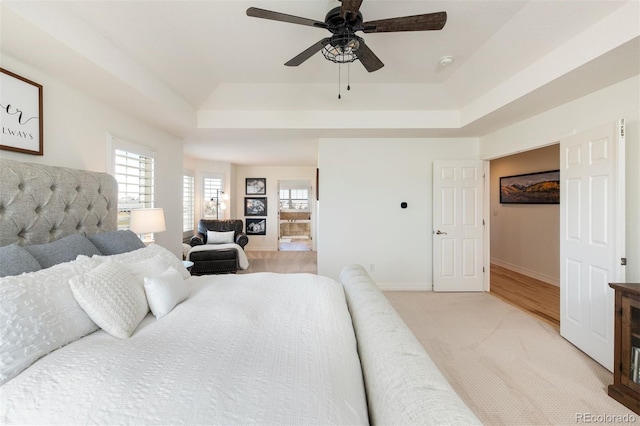 bedroom featuring baseboards, ceiling fan, a raised ceiling, and light colored carpet