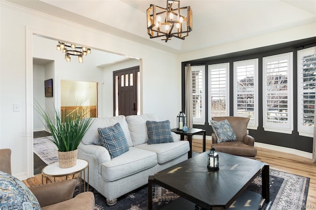 living room with a chandelier, ornamental molding, baseboards, and wood finished floors