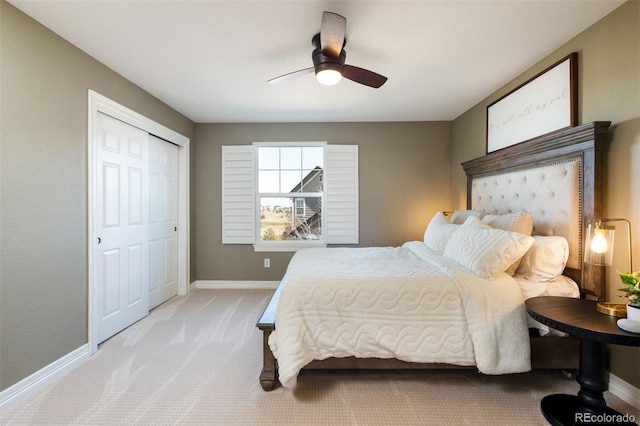 bedroom featuring baseboards, ceiling fan, a closet, and light colored carpet