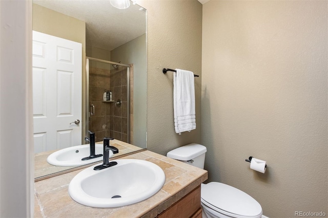 bathroom with toilet, a textured wall, a stall shower, and vanity