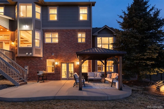 rear view of house featuring brick siding, a patio, an outdoor living space, and stairs