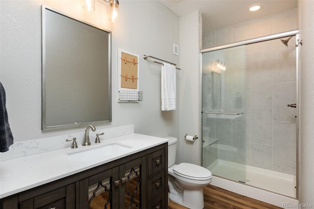 full bathroom featuring vanity, wood finished floors, a shower stall, and toilet