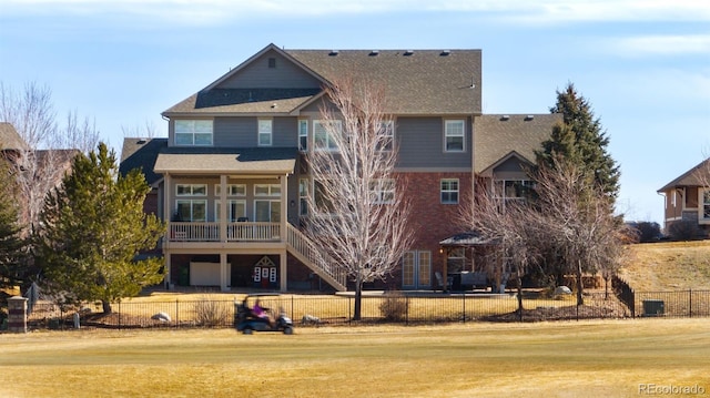 rear view of property featuring a fenced front yard, an attached garage, dirt driveway, stairway, and a lawn