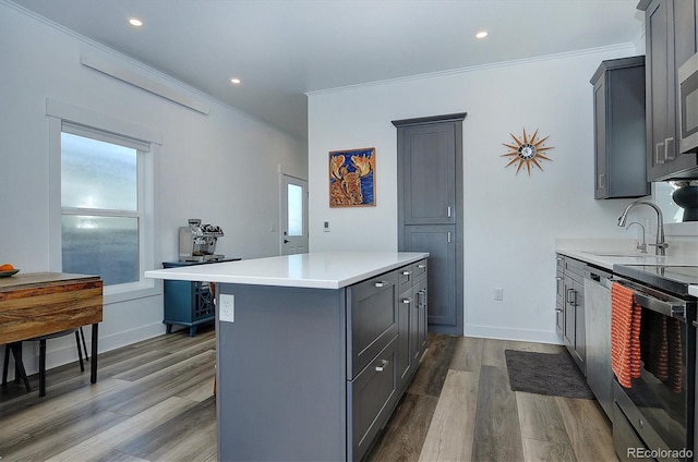 kitchen with appliances with stainless steel finishes, gray cabinets, a kitchen island, and dark wood-type flooring