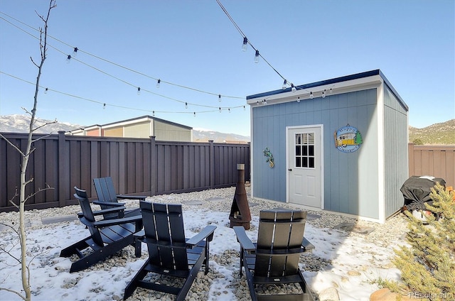 snow covered patio featuring a mountain view and a storage unit