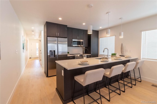 kitchen with sink, hanging light fixtures, a kitchen breakfast bar, stainless steel appliances, and kitchen peninsula