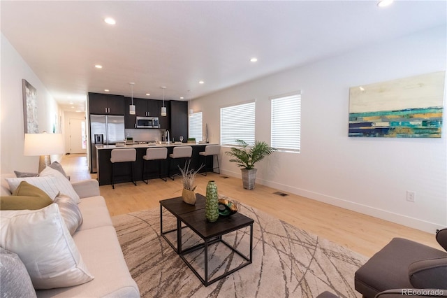 living room featuring sink and light hardwood / wood-style flooring