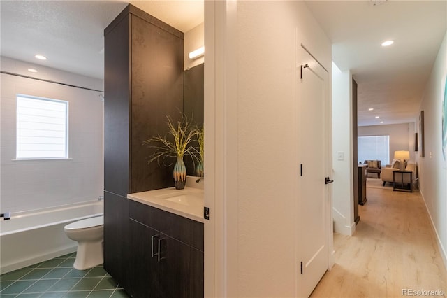 full bathroom featuring vanity, tiled shower / bath combo, wood-type flooring, and toilet