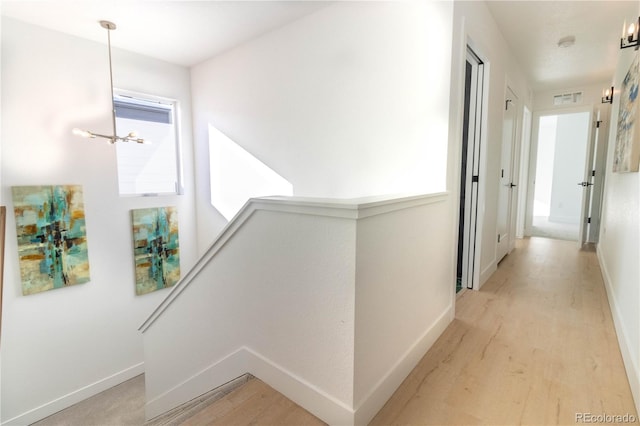 hall featuring an inviting chandelier and light hardwood / wood-style flooring