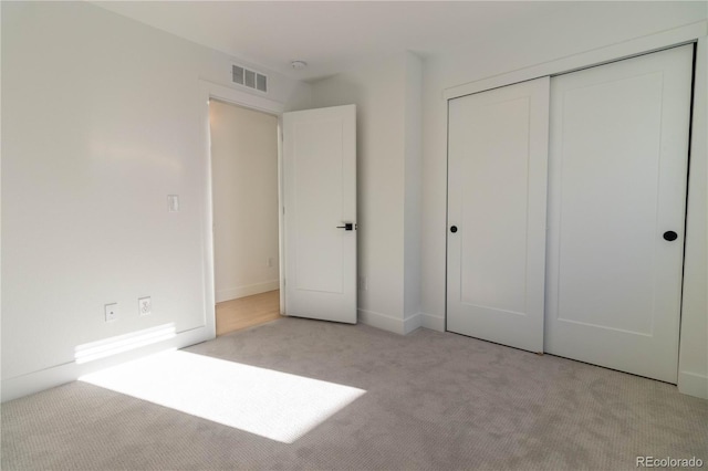 unfurnished bedroom featuring light carpet and a closet