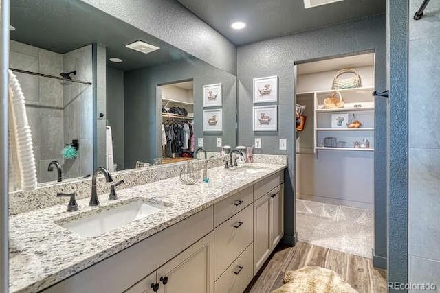 336 Arrowhead Dr, Florence, CO 81226 - bathroom featuring wood finished floors, a stall shower, double vanity, and a walk in closet