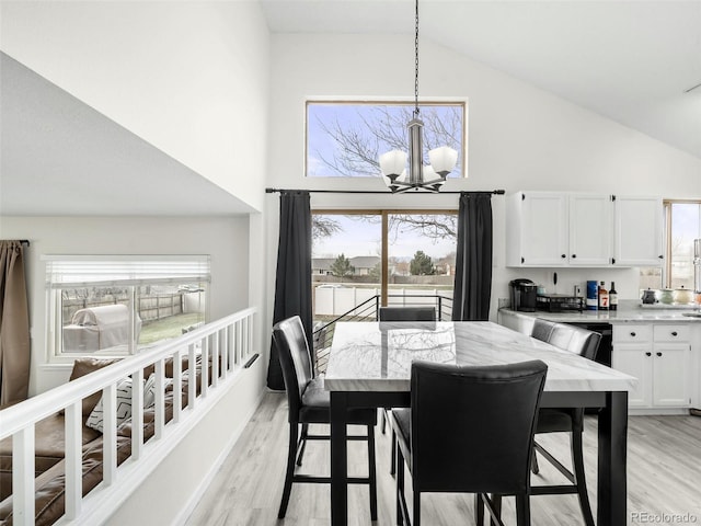 dining space featuring a chandelier, high vaulted ceiling, and light wood-type flooring