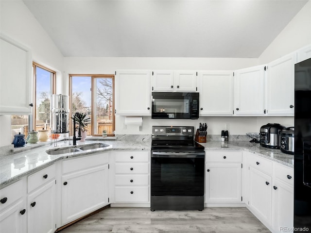 kitchen with black appliances, white cabinetry, and vaulted ceiling