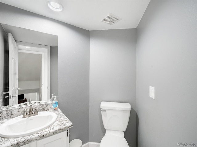 bathroom with toilet, vanity, and visible vents