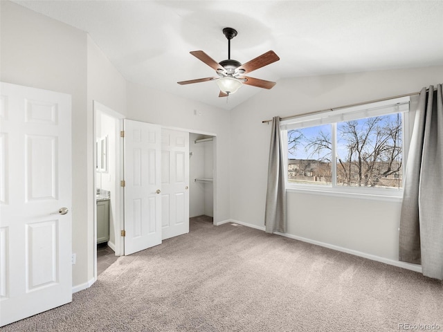 unfurnished bedroom featuring carpet floors, baseboards, a closet, and lofted ceiling