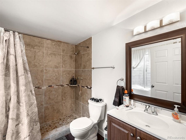 full bathroom featuring a tile shower, vanity, and toilet