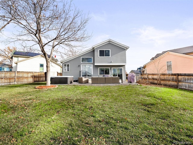 back of property featuring a hot tub, a lawn, an outdoor living space, and a fenced backyard