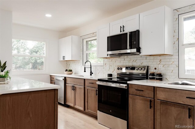 1617 S Quitman St, Denver, CO 80219 - kitchen with appliances with stainless steel finishes, a sink, light countertops, light wood-type flooring, and white cabinets