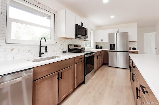 1617 S Quitman St, Denver, CO 80219 - kitchen with stainless steel appliances, a sink, backsplash, light wood-style flooring, and light countertops